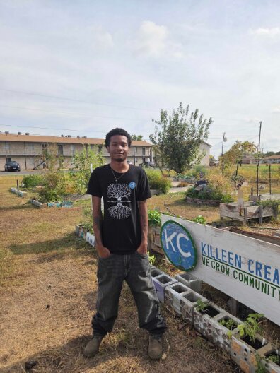 New AmeriCorps member Landon Cobbins standing by the Killeen Creators garden sign he now helps care for.